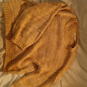 Gulmelerad stickad tröja från NA-KD - Supermysig stickad tröja från NA-KD i gulmelerad färg. Tröjan har rund halsringning, ribbade muddar och lång ärm. Perfekt för lager på lager och chill höst- och vinterstil.