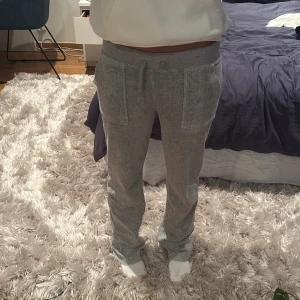 Grå mjukisbyxor Juicy Couture XS - Grå mjukisbyxor från Juicy Couture i storlek XS. Byxorna har snörning i midjan, stora fickor fram och en bakficka med knapp. Mjukt material som känns riktigt skönt mot huden. Perfekta för chill dagar hemma eller när du vill vara extra bekväm.
