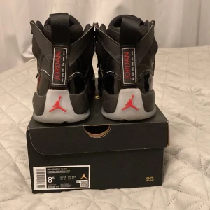 Air Jordan high skor  - Säljer ett par svarta Nike Air Jordan 6 Rings med röda detaljer och vit sula. Skorna har en blandning av skinn och syntetmaterial, snörning och en hög siluett. Ikonisk Jumpman-logga på hälen och tungan. Perfekta för dig som gillar streetwear och basketinspirerad stil.