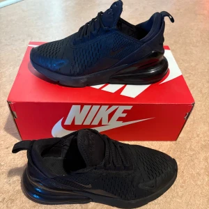 Nike Air Max 270 Black sneakers - Nike Air Max 270 Black sneakers med helsvart mesh- och syntetöverdel, stor synlig Air-enhet i hälen och diskreta Nike-loggor. Skorna har snörning och en sportig, modern look som passar perfekt till streetwear. Grymt sköna och lätta på foten.