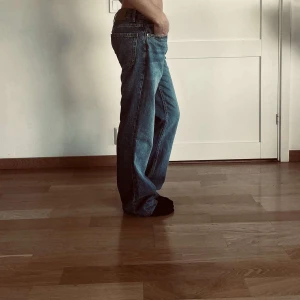 Blåa baggy/straight jeans med låg midja  - Säljer ett par blåa jeans med lite baggy/straight leg, och är lågmidjade! Supersnygga och trendiga. 
