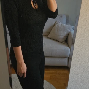 Svart topp - Svart ribbad topo med trekvartsärm och snygg snörning vid halsringningen. Passar storlek S-M skulle jag säga.