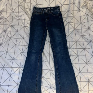 Mörkblå bootcut jeans från Denim 1953 - Snygga mörkblå jeans från Denim 1953, modell Susan. Klassisk femficksdesign, bootcut-ben och normal passform. Tillverkade i slitstarkt jeanstyg med lätt tvättad look. Perfekta för dig som gillar en tidlös stil med lite extra vidd nertill. 