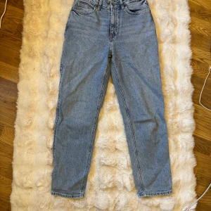 Blå jeans hög midja HM - Blå jeans med hög midja och raka ben. Jeansen har fem fickor, knappgylf och är tillverkade i robust denim. Perfekta för dig som gillar en tidlös och avslappnad stil.