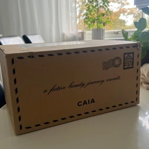 CAIA Adventskalender 2025 - Säljer en CAIA Advent Calendar i exklusiv presentförpackning. Kalendern innehåller flera olika sminkprodukter från CAIA, perfekt för dig som vill testa nya favoriter. Boxen är ljusrosa med svart rosett och etikett, och levereras i originalkartong.
