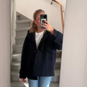 Mörkblå kappa från COS - Säljer en mörkblå kappa med huva. Perfekt till hösten! Från cos. Fint skick