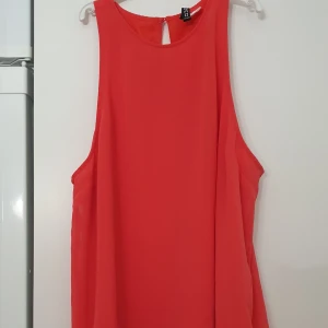 Topp - Snygg röd topp från H&M med ärmlös design och rund halsringning. Toppen har en lätt A-linjeformad siluett och knäppning med knapp i nacken. Tillverkad i ett tunt, flowy material som ger en luftig känsla.