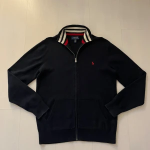 Svart kofta från Polo Ralph Lauren - Svart kofta från Polo Ralph Lauren. Står Storlek L men sitter som S. fint skick men finns ett litet hål vid axeln se bild. Kom privat för mer info