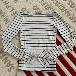 Randig långärmad tröja Gina Tricot - Säljer en vit långärmad tröja från Gina Tricot med svarta horisontella ränder. Tröjan har en smal passform och är tillverkad i mjuk bomull, perfekt för lager-på-lager eller som den är. Enkel och stilren design som funkar året runt.