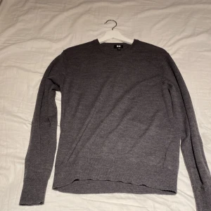 Grå stickad tröja från Uniqlo - En stilren grå stickad tröja från Uniqlo i storlek S. Tröjan har rund halsringning och långa ärmar, perfekt för lager-på-lager. Enkel och clean design som funkar till det mesta. Materialet känns mjukt och lätt, vilket gör den skön att bära.