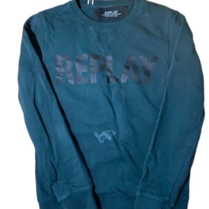 Mörkgrön sweatshirt från Replay - Cool mörkgrön sweatshirt från Replay med stor logga i svart på bröstet. Tröjan har rund hals och långa ärmar, tillverkad i mjuk bomull. Perfekt för dig som gillar streetwear och vill ha en enkel men snygg look.