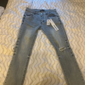 Purple jeans - Säljer ett par ljusblå jeans från Purple Brand med snygga slitningar. Modellen är slim/skinny och har klassisk femficksdesign, knappgylf och tag kvar. Perfekt för dig som gillar streetstyle och vill ha en cool look.