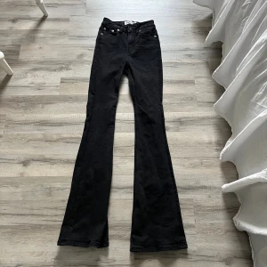 Svarta bootcut jeans  - Svarta jeans med klassisk femficksdesign och bootcut-ben. Snyggt högmidjade och tillverkade i mjukt jeansmaterial som sitter bekvämt. Perfekta för dig som gillar en tidlös och cool stil.