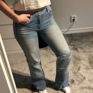 Blå bootcut jeans  - Snygga blå jeans med bootcut passform och slitna detaljer och olika färger. Jeansen har mid midja. Super snygga och trendiga!