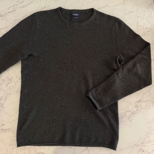 Mörkgrå grovstickad tröja Jack & Jones - Säljer en mörkgrå stickad tröja från Jack & Jones Premium i storlek S. Tröjan har ett snyggt strukturerat mönster, rund hals och långa ärmar. Perfekt för dig som gillar stilrena och bekväma plagg med lite extra textur. Perfekt skick. 