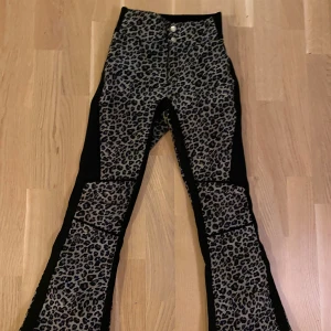 Leopardmönstrade täckbyxor 8848 Altitude - Snygga täckbyxor från 8848 Altitude i leopardmönster med svarta paneler. Byxorna har hög midja, quiltade detaljer och dragkedjor vid bensluten. Materialet är slitstarkt och fodrat för extra värme, perfekt för kalla dagar. Unik look som sticker ut i backen!