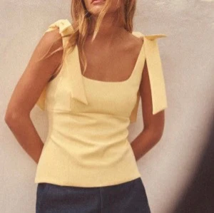 Zara topp - Snygg ljusgul linnetopp med breda axelband som knyts i stora rosetter på axlarna. Toppen har en rak, något figurnära passform och fyrkantig ringning. Perfekt för en somrig look. Säljs inte längre, skriv för fler bilder eller frågor 💓 