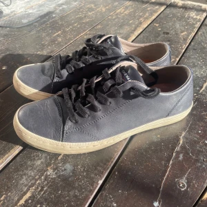 Mörkblåa sneakers från Cole Haan - Snygga mörkblåa sneakers från Cole Haan med klassisk design och rund tå. Skorna har svart snörning, ovandel i skinn och en beige platt sula. Diskret logga på hälen och tungan. Perfekta för dig som gillar stilrena och tidlösa sneakers. NÄSTINTILL OANVÄNDA SKOR, NYPRIS:2399Kr. MITT PRIS: 649Kr ✅