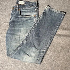 Wrangler Ben jeans blå W32 L32 - Snygga blå Wrangler Ben jeans med klassisk femficksdesign och coolt sliten tvätt. De har raka ben och normal passform, med bruna detaljer på bakfickan och tydliga sömmar. Perfekt för dig som gillar en avslappnad och tidlös jeansstil.