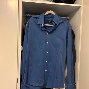 Blå skjorta från eton - blå skjorta från eton i bomull, inga defekter med skjorta, materialet är lite stretchigt och luftigt. Perfekt för att ha under en tröja utan att det ska bli för varmt, storlek M