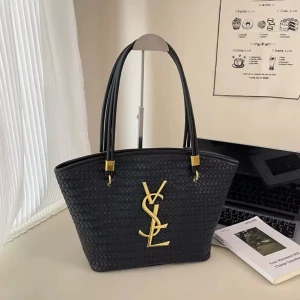 Svart YSL handväska i flätat skinn - Stilren svart handväska från YSL med flätad struktur och stora guldiga YSL-bokstäver framtill. Väskan har dubbla handtag med gulddetaljer och är tillverkad i skinn. Perfekt för dig som vill ha en lyxig och trendig accessoar.