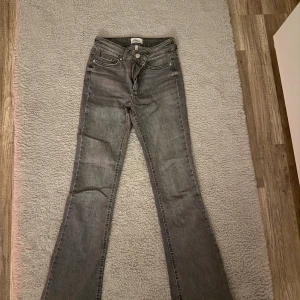 Grå bootcut jeans från Only - Snygga grå jeans från Only med bootcut passform och klassisk femficksdesign. Dom ör i storlek S Jeansen har låg midja och är tillverkade i mjukt denimtyg med lätt stretch för skön komfort. 