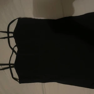 Svart linnetopp - Svart linnetopp från Rainbow med dubbla smala axelband som korsar varandra för en cool detalj. Toppen är ärmlös och har en enkel, rak form. Materialet känns mjukt och lätt, perfekt för varma dagar. Snygg att styla med jeans eller kjol.