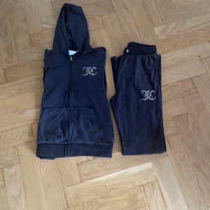 Mörkblå Juicy Couture hoodie med strass - Säljer en mörkblå hoodie från Juicy Couture i mjuk velour med strassdetaljer på bröstet och stor Juicy Couture-logga på ryggen. Tröjan har huva, dragkedja, långa ärmar och fickor framtill. Perfekt för chill dagar och ikonisk 00-talsstil.