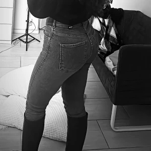 Mörkgrå skinny jeans med hög midja - Snygga mörkgrå skinny jeans med hög midja och klassiska bakfickor. Jeansen har en tight passform och är perfekta att styla med boots eller sneakers. Materialet är stretchigt och bekvämt för en smickrande siluett.