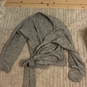 Grå stickad kofta man knyter - Köpt på zalando märket värkar vara even&odd. Ser inte så bra ut på mitt golv men är jättefin och mysig. Nästan aldrig använt.