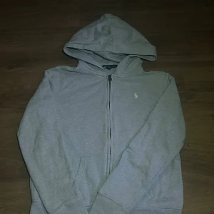 Ralph lauren zip hoodie - 💎 Superfin Ralph Lauren zip hoodie 💎 Storlek 152 (barn) 👕 Färg: Ljusblå 💙 – stilren, fräsch och passar till allt!  🔥 Jättebra skick – nästan som ny, inga fläckar eller slitage ✨ Perfekt för höst/vår 🍂🌸 eller som mysig hoodie året runt 😍  🦋 Klassisk Ralph Lauren-stil med loggan framtill – både bekväm och snygg 👌 💨 Dragkedja framtill & mjukt material för extra komfort!  📦 Skickas snabbt 💙 Passa på innan den försvinner! 💙