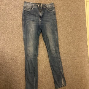 Blå skinny jeans med slits nertill - Snygga blå skinny jeans med hög midja och slits nertill på benen. Klassisk femficksmodell med dragkedja och knapp framtill. Perfekta för dig som gillar en tight passform och vill ha en liten detalj som sticker ut.
