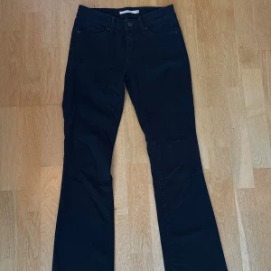 Svarta bootcut jeans från Levi's - Svarta jeans från Levi's med bootcut passform, i modellen 715 och klassisk femficksdesign. Låg/medelhög midja. Jeansen har en snygg svart läderpatch bak i midjan och är tillverkade i ett stretchigt bomullsmaterial för extra komfort. Perfekta för dig som gillar en tidlös och clean look. Köpte på Vinted med de va tyvärr för små :(. De är i superfint skick, inga slitningar eller andra defekter. Storlek: 25. Innerbenslängd: 78cm. Säljer för: 250kr!