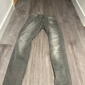 Grå skinny jeans G-Star RAW Revend - Grå skinny jeans från G-Star RAW, modell Revend. Jeansen har slitna detaljer och diskreta hål på låren och vid fickorna för en cool, använd look. Klassisk femficksmodell med knapp och dragkedja. Perfekta för dig som gillar en smal passform och streetstil.