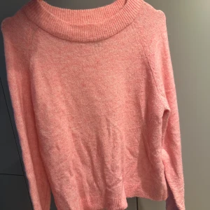 Rosa stickad tröja från Vero Moda - Mysig rosa stickad tröja från Vero Moda i storlek M. Tröjan har en bred ribbad krage och långa ärmar, perfekt för att hålla dig varm under kyliga dagar.                  Nypris 399