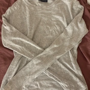 Grå långärmad tröja Brandy Melville - En basic ljusgrå långärmad tröja från Brandy Melville. Tröjan har rund halsringning och är tillverkad i mjuk bomullsmix, perfekt för lager-på-lager eller chill dagar. Enkel och stilren design som funkar till allt.