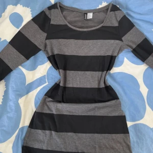 Randig svart och grå klänning/tröja H&M🍁 - Snygg kortklänning från H&M med breda svarta och grå ränder. Klänningen har rund halsringning och trekvartsärm. Den är figurnära och gjord i mjuk bomull, perfekt för en chill och stilren look. Den går att använda som en rätt lång T-shirt eller som en kortare klänning!!❤️❤️