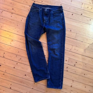 Levi's 551Z Straight jeans blå W33 L34 - Säljer ett par klassiska Levi's 551Z Straight jeans i mörkblå denim. Modellen har rak passform, fem fickor och traditionell knappgylf. Perfekta för dig som gillar en tidlös och avslappnad look. Ikonisk Levi's-lapp bak i midjan. Inte mycket använda pga snabbt urväxta. 