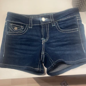omgjorda jeans till shorts från Gina tricot hos en skräddare - Mörkblå jeansshorts från Gina Tricot med kontrasterande vita sömmar och klassiska fickor fram och bak. Shortsen har knapp och dragkedja framtill samt bälteshällor. Perfekta för sommardagar och enkel att matcha med olika toppar.