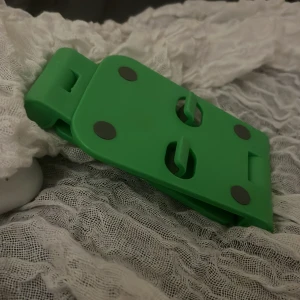Grön justerbar mobilställ - Praktisk grön mobilställ i plast, hopfällbar och justerbar för olika vinklar. Perfekt för att hålla din mobil upprätt vid videosamtal, film eller surf. Kompakt design, lätt att ta med. Inga synliga defekter eller slitage, 