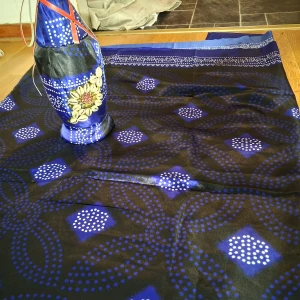 Blå långkjol med mönster från Dahabo - Snygg långkjol i blått och svart med unikt prickigt och geometriskt mönster. Kjolen har en glansig finish och bred bård upptill. Perfekt för dig som gillar färgstarka och traditionella plagg med modern twist.