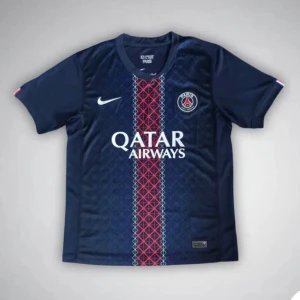 PSG matchtröja Nike blå röd - Snygg PSG fotbollströja från Nike i mörkblått med röd och vit rand längs mitten. Tröjan har korta ärmar, klubbmärke på bröstet och Qatar Airways-tryck. Tillverkad i lätt och ventilerande material, perfekt för match eller träning.