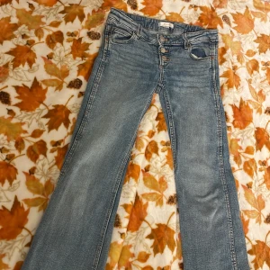 Blå bootcut jeans från Gina Tricot - Snygga blå jeans från Gina Tricot i storlek 146. Modellen har bootcut-ben, klassisk femficksdesign och flera silverfärgade knappar framtill. Jeansen är tillverkade i jeansmaterial med en lätt tvättad look och har normal passform. Har dock ett litet hål som jag försökt sy igen på höger bakficka