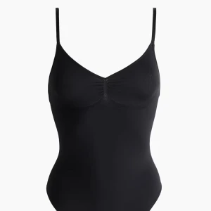 Svart linnebody med smala axelband - Säljer en svart oanvänd, tight linnebody i storlek XS med smala justerbara axelband och v-ringad hals. Bodyn har lätt rynk vid bysten och är tillverkad i stretchigt syntetmaterial som sitter skönt mot kroppen. 