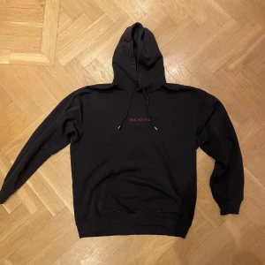 Svart hoodie från Vailent med tryck - Svart limited hoodie från Vailent (köpt på Carlings) med röd broderad text 'SEE NO EVIL' på bröstet och stort tryck med fladdermus och text på ryggen. Hoodien har snörning i huvan, känguruficka och långa ärmar. Perfekt för dig som gillar streetwear med coola detaljer. Använd men i bra skick.