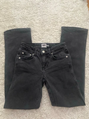 Svarta raka jeans från 157 - Säljer ett par svarta jeans från 157 och klassisk femficksdesign. Jeansen har silverfärgade nitar och knapp, samt bälteshällor. Materialet är denim i bomull  och elastan. Jeansen är kortade i benen! 