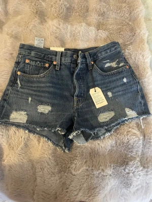 Levi's 501 blå jeansshorts med slitningar - Snygga blå jeansshorts från Levi's modell 501 med råa kanter och slitna detaljer. Oanvända med prislapp kvar. Skriv om ni har frågor och kolla gärna in andra kläder på min sida!🩷