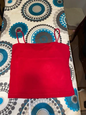 Röd linnetopp från Gina Tricot - Snygg röd linnetopp från Gina Tricot med tunna axelband. Toppen är croppad och har en enkel, stilren design som passar perfekt till jeans eller kjol. Tillverkad i mjukt material som känns skönt mot huden.