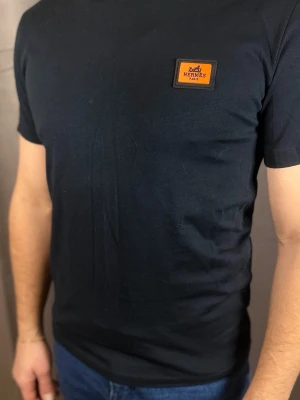 Svart t-shirt  - . Klassisk passform och korta ärmar. Tillverkad i mjukt bomullstyg som känns skönt mot huden. Perfekt för dig som gillar stilrena och exklusiva plagg.