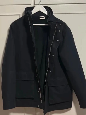 Svart parkas från GANT - Stilren mörkblå parkas från Gant. Perfekt för dig som vill ha en enkel men snygg jacka till höst och vinter. Nypris: 5500. Skick: Använd endast ett fåtal gånger. Tveka inte på att höra av dig om du har frågor eller funderingar!